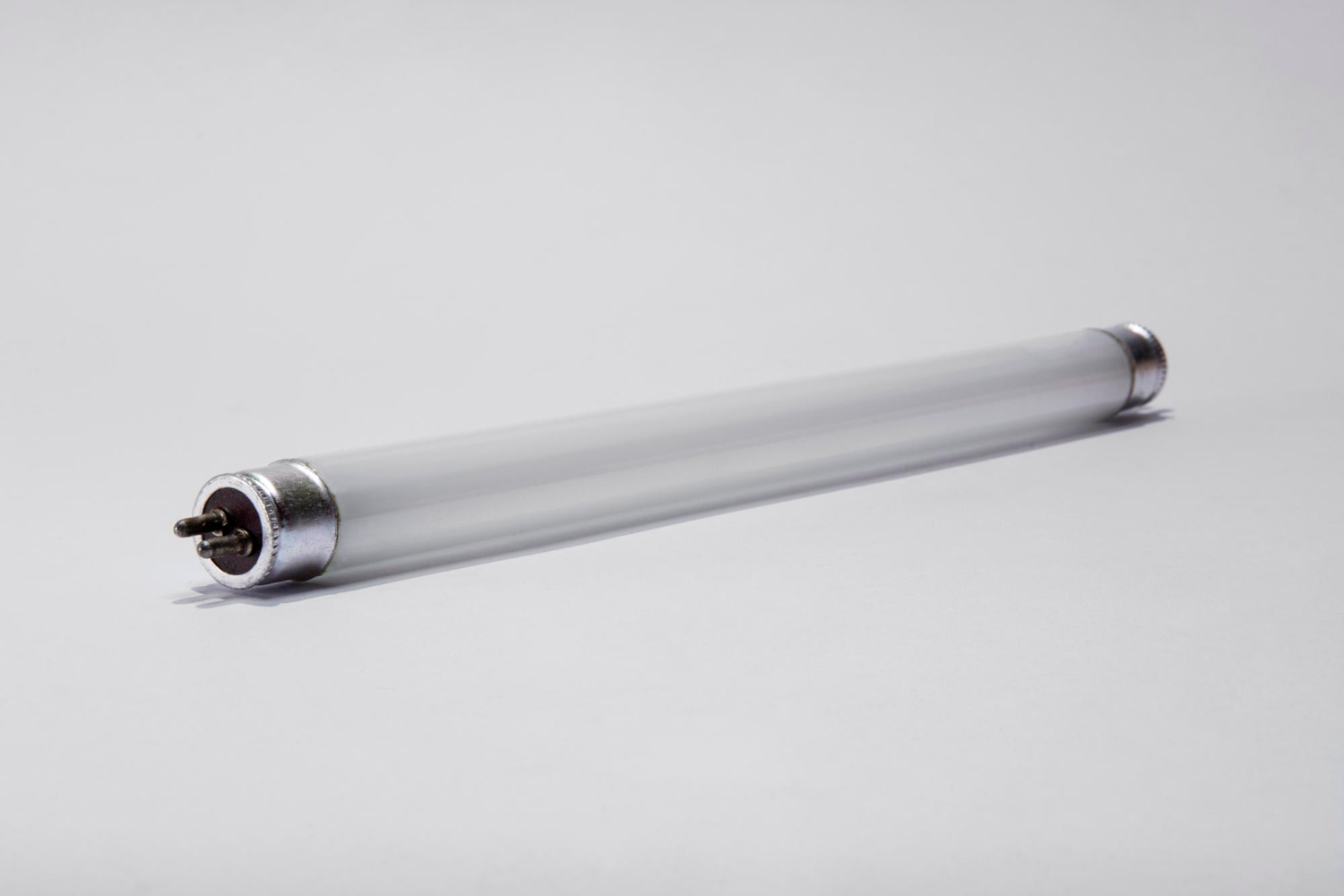 A fluorescent tube light lying on a plain white surface.